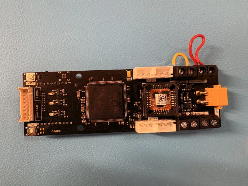 Populated flight-computer circuit board on a blue surface