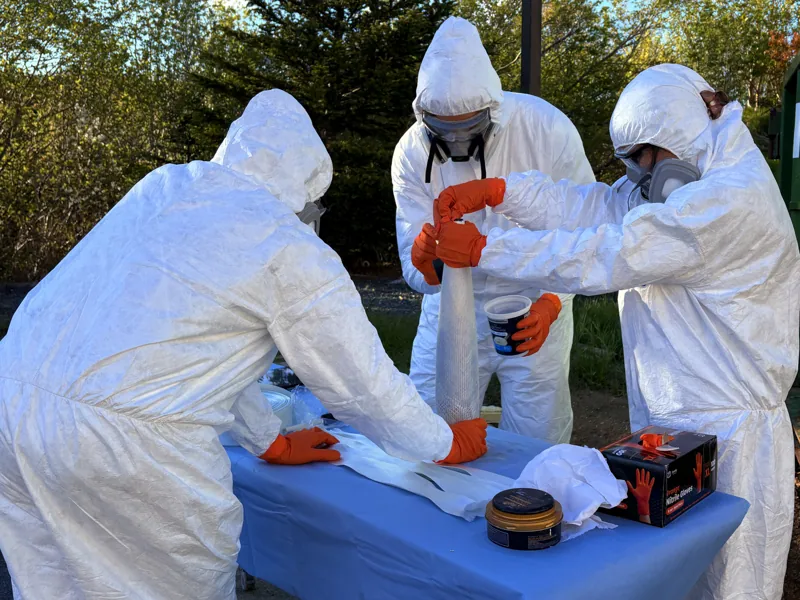 Three team members working with fabric around the nose-cone form