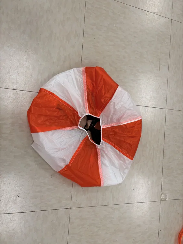 Orange and white parachute canopy laid out on the floor