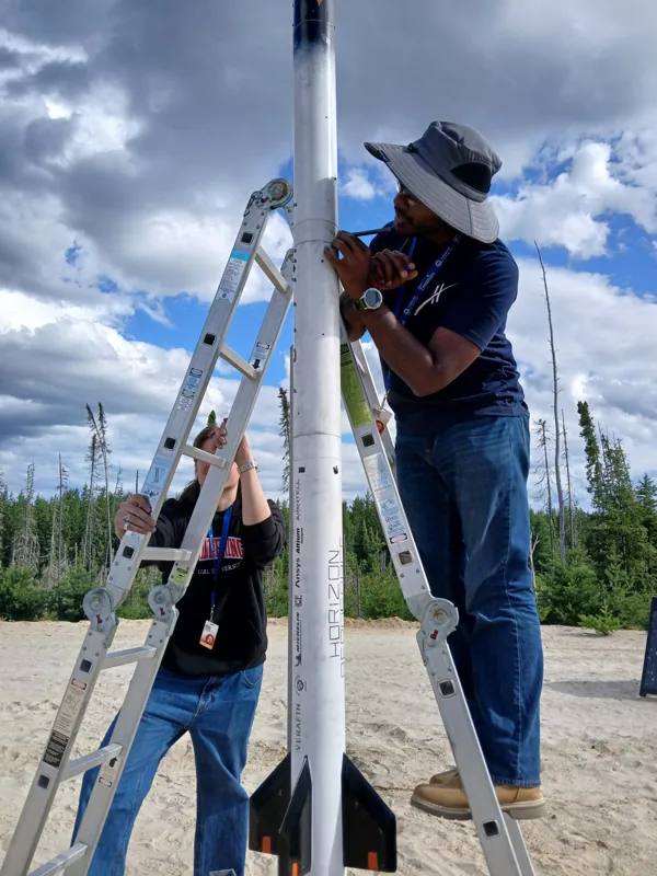 Team member working on Puffin-1 from a ladder at the launch rail